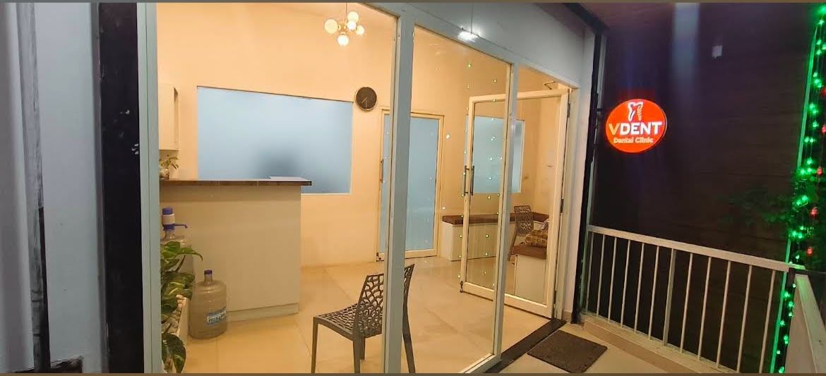Glass entrance of the clinic on the first floor with the illuminated V Dent sign